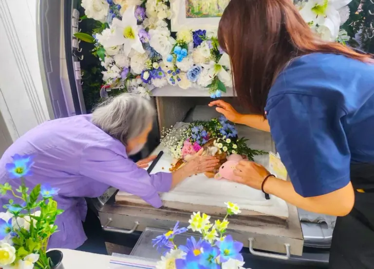 火葬車内でお花に囲まれたペットにお別れをする様子